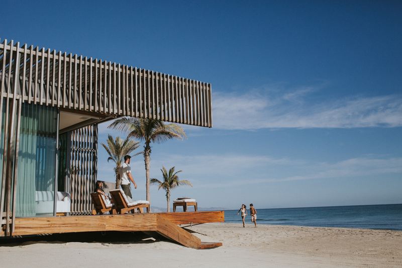 A family at a beachfront residence, with children running on the sand