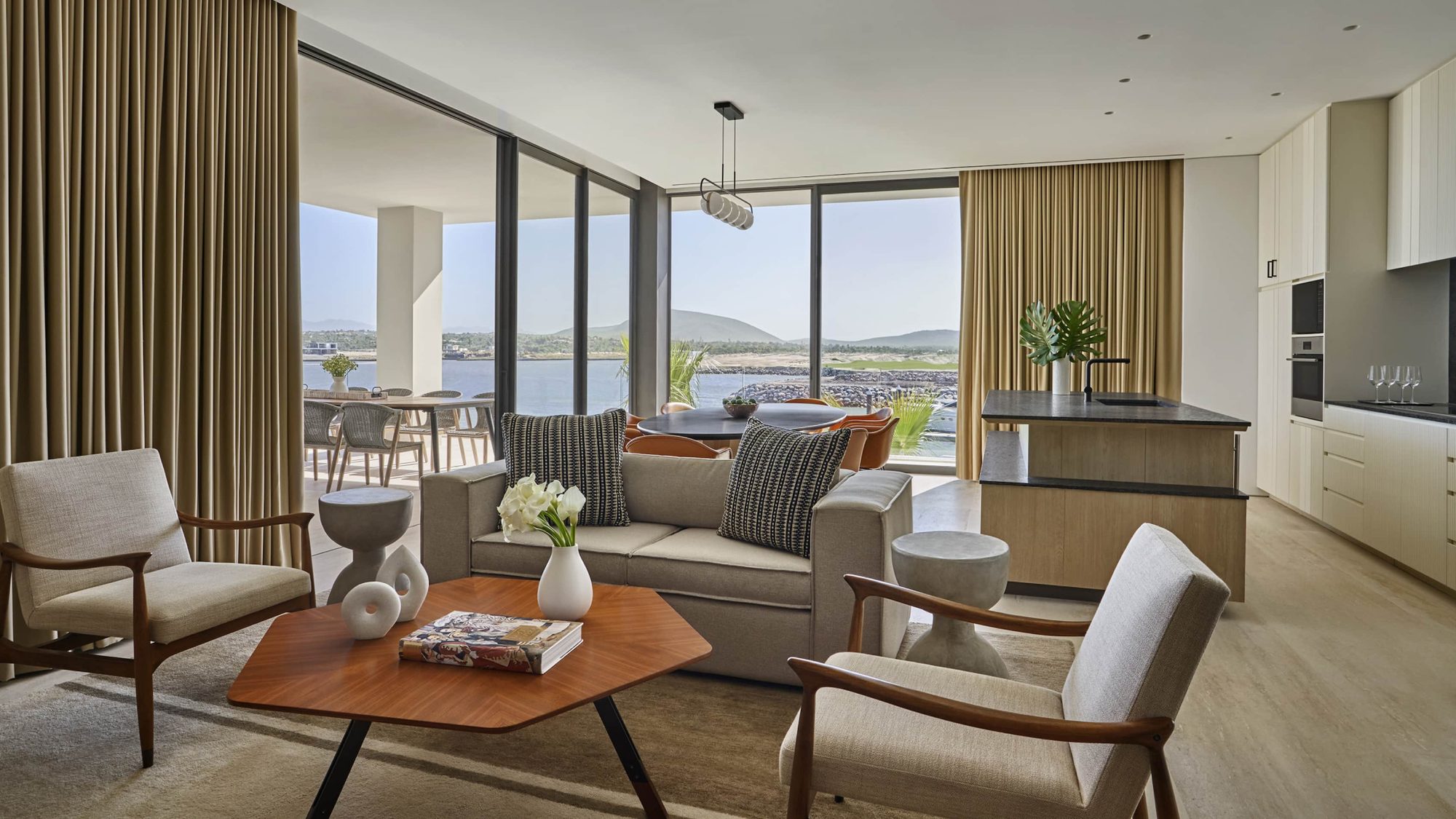 The living room of a Four Seasons Marina Residence, with the marina and the mountains beyond the windows